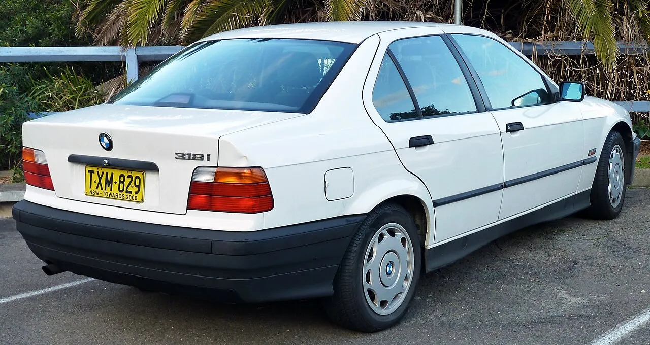 White BMW E36 318i sedan, rear three-quarter view